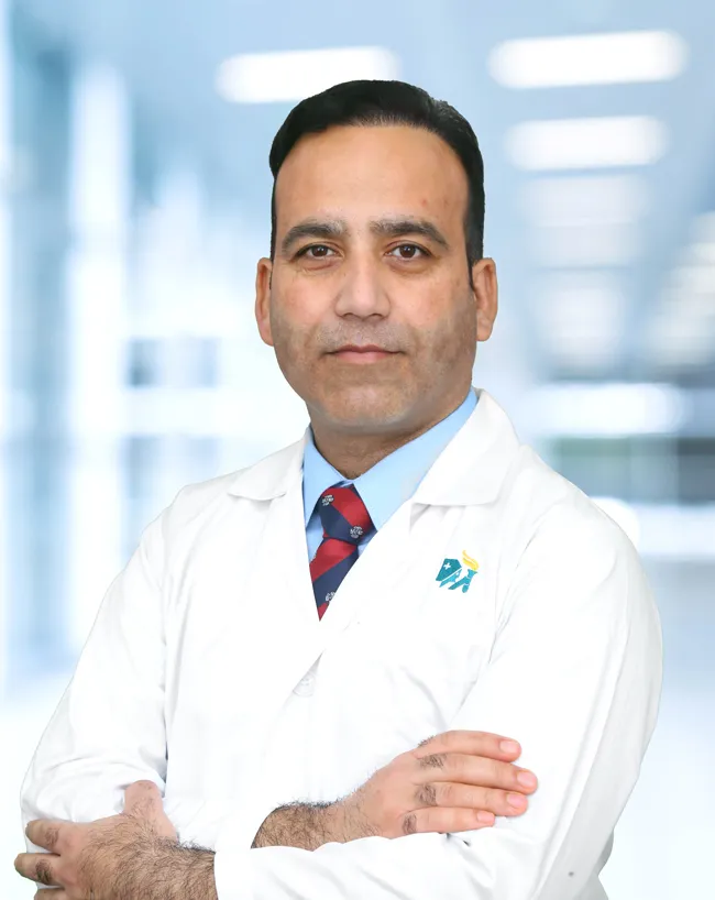Dr. Asif Mehraj in a white coat, arms folded, in a hospital corridor