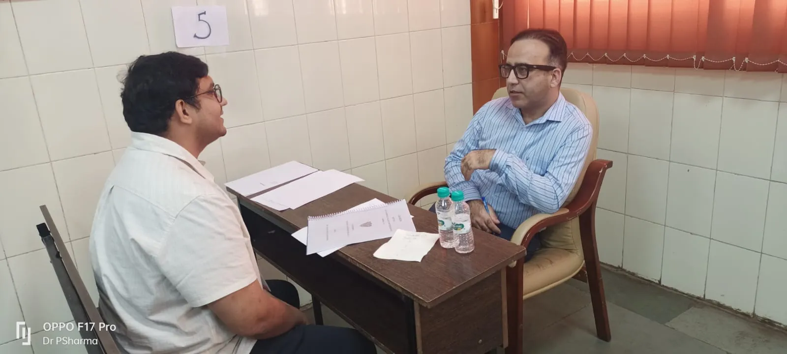 Dr. Asif Mehraj discussing symptoms with a patient across his clinic desk