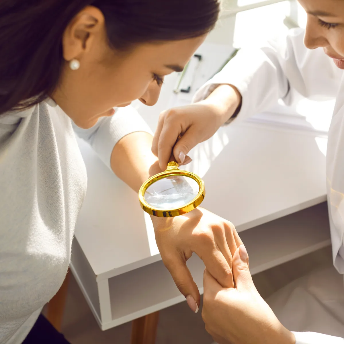 Dermatology team examining a patient’s skin with a magnifier during a medical dermatology visit