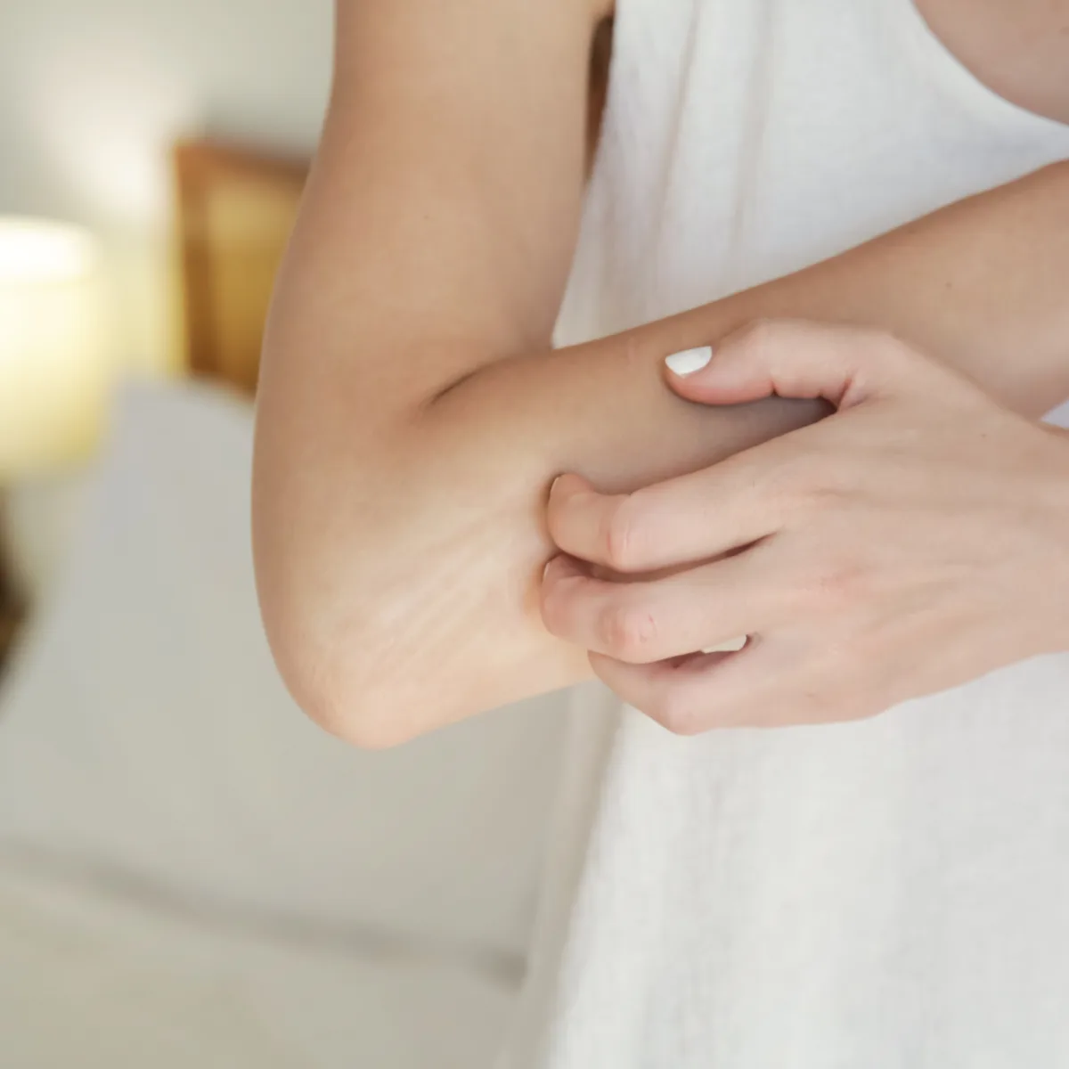 Person scratching dry, irritated skin on their forearm during an eczema flare-up