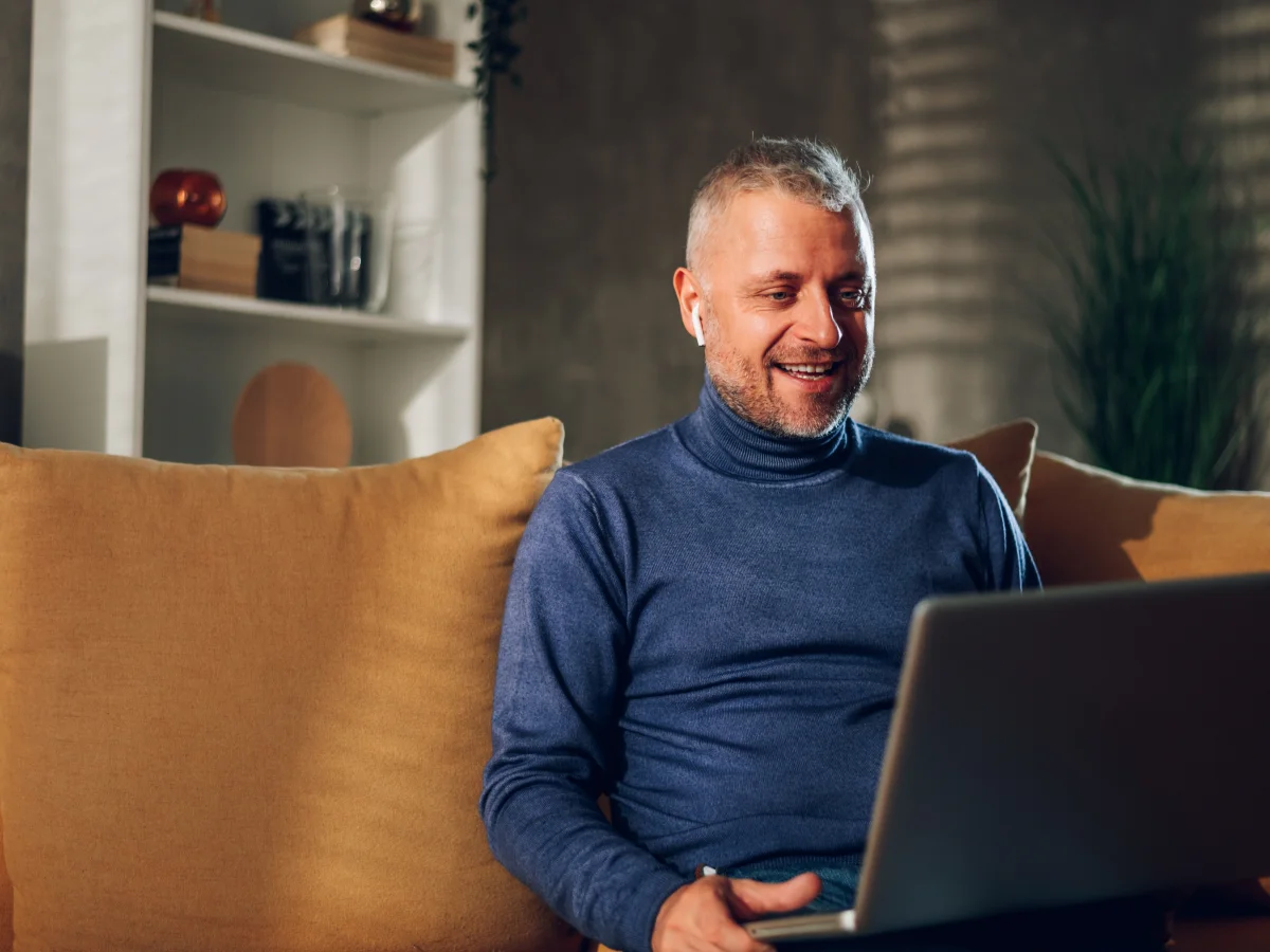 Man at home using his laptop to arrange a hair restoration consultation