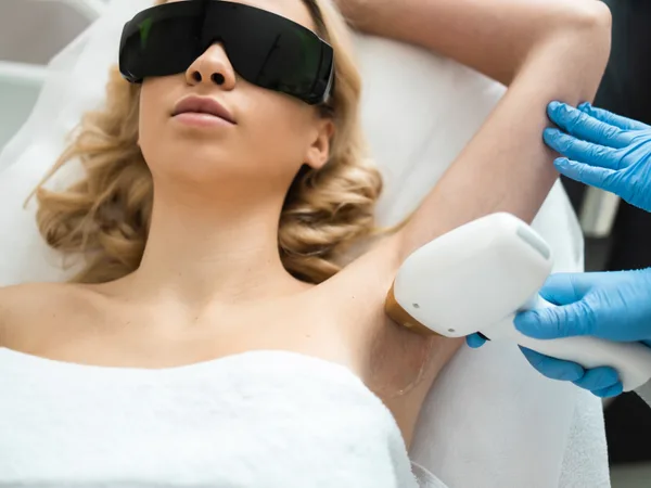 Clinician performing a laser hair removal treatment on a patient wearing protective eyewear