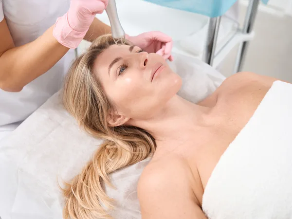 Provider performing a laser skin resurfacing treatment on a patient's face