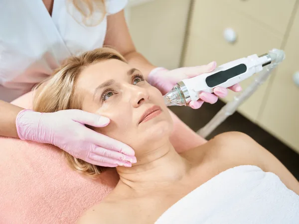 Provider performing a microneedling skin rejuvenation treatment on a patient's face