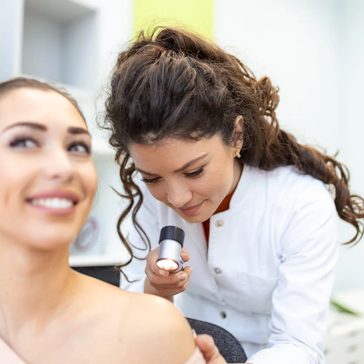 Dermatologist examining a mole with a dermatoscope during a skin cancer check