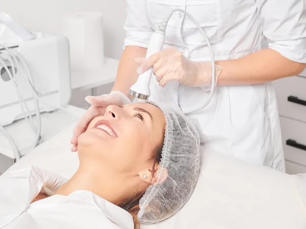 Provider delivering an ultrasound skin tightening treatment to a patient's face