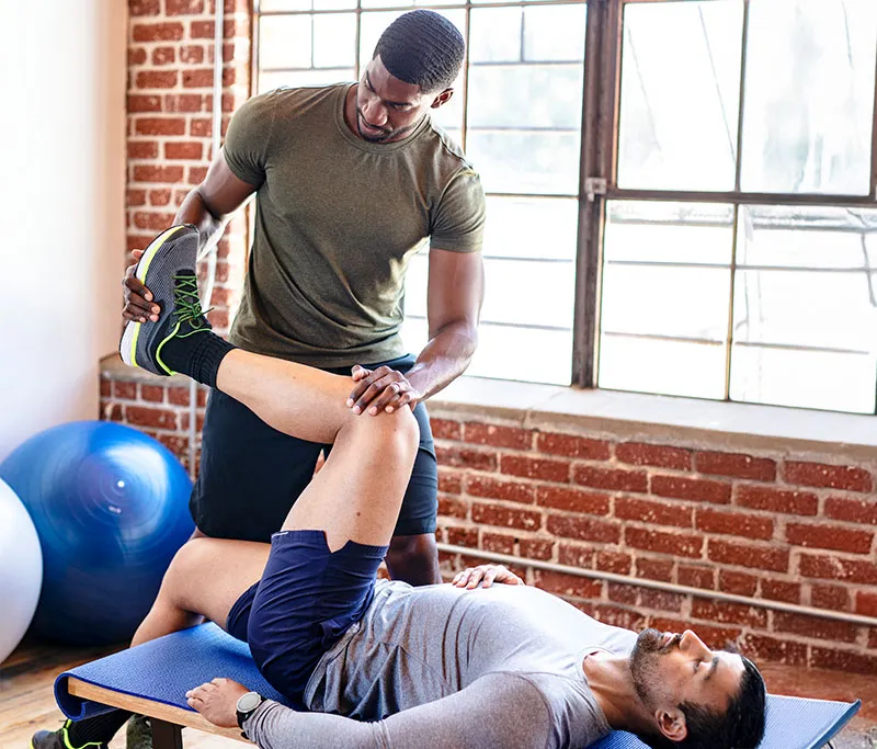 Patient doing physical rehabilitation helped by therapists