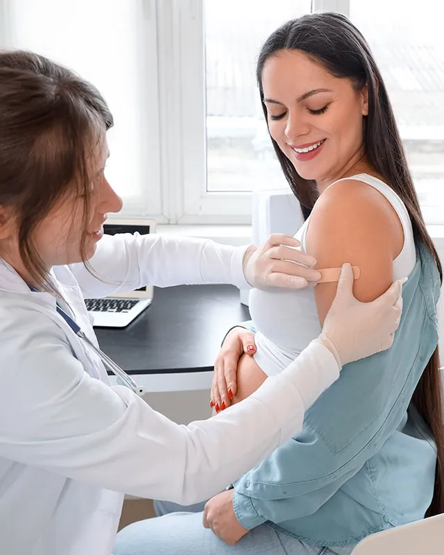 Doctor placing a bandage on a smiling patient after her flu shot
