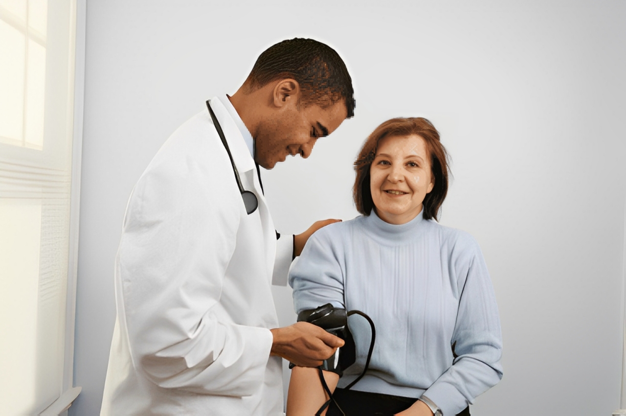 Smiling middle-aged woman getting her blood pressure checked by a doctor in a clinical setting.