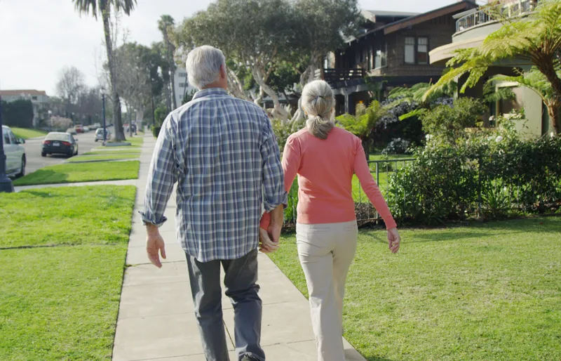 Senior couple walking together through a quiet Orange County neighborhood