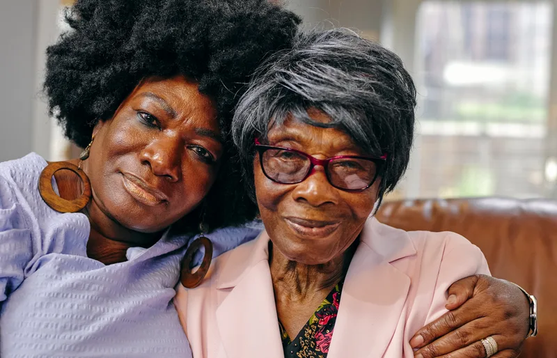 Adult daughter sitting close to her elderly mother, sharing a supportive moment at home