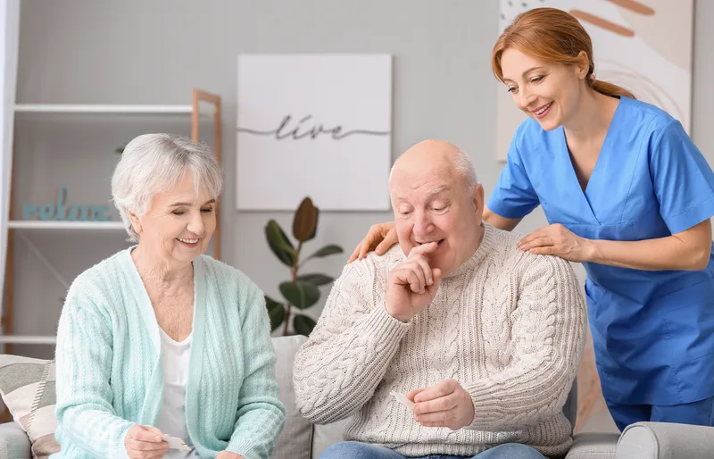 Care team member supporting a senior couple in a dementia care community lounge