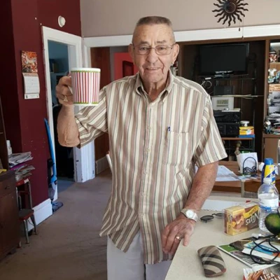 Senior man standing in his kitchen raising a striped mug toward the camera