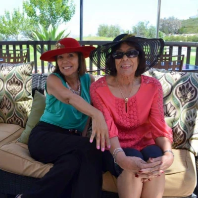 Two women in wide sun hats relaxing side by side on an outdoor patio sofa