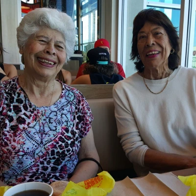 Two senior women laughing together in a booth at a casual restaurant