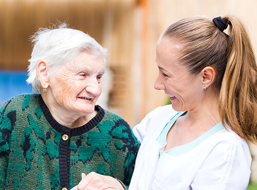 Female caregiver holding hand of elderly patient