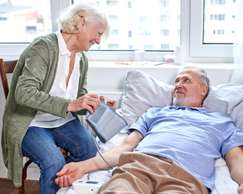 Female caregiver checking elderly’s blood pressure