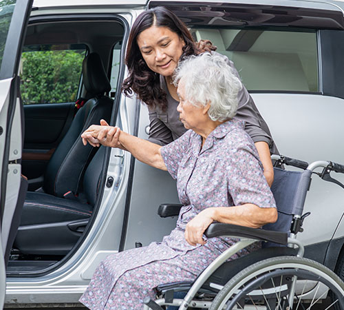 Female caregiver helping elderly in transportation