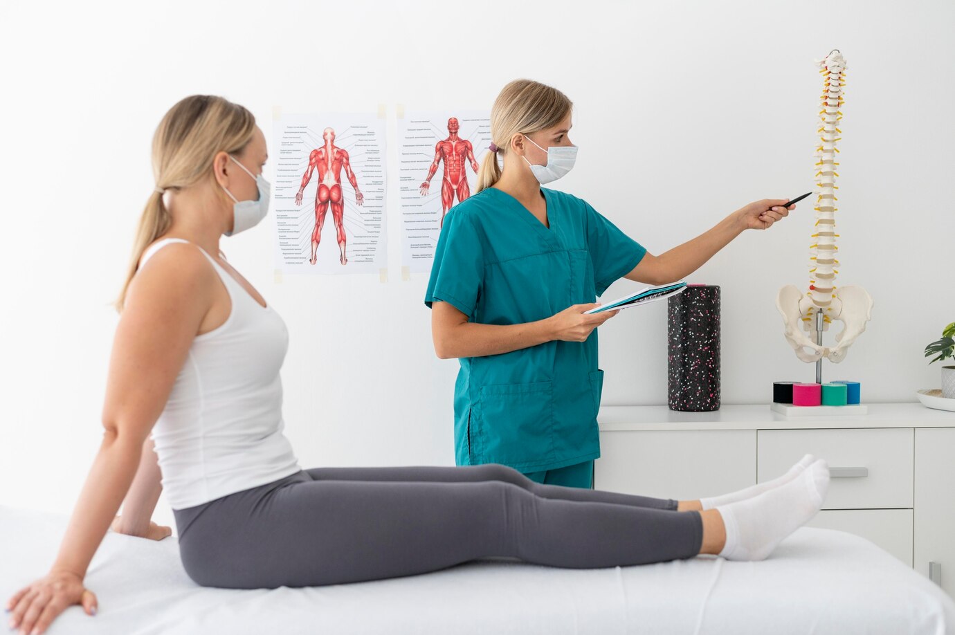 Discussion of herniated disc symptoms with patient using spinal anatomy model A healthcare professional explaining herniated disc symptoms to a patient using a spine model during a consultation.