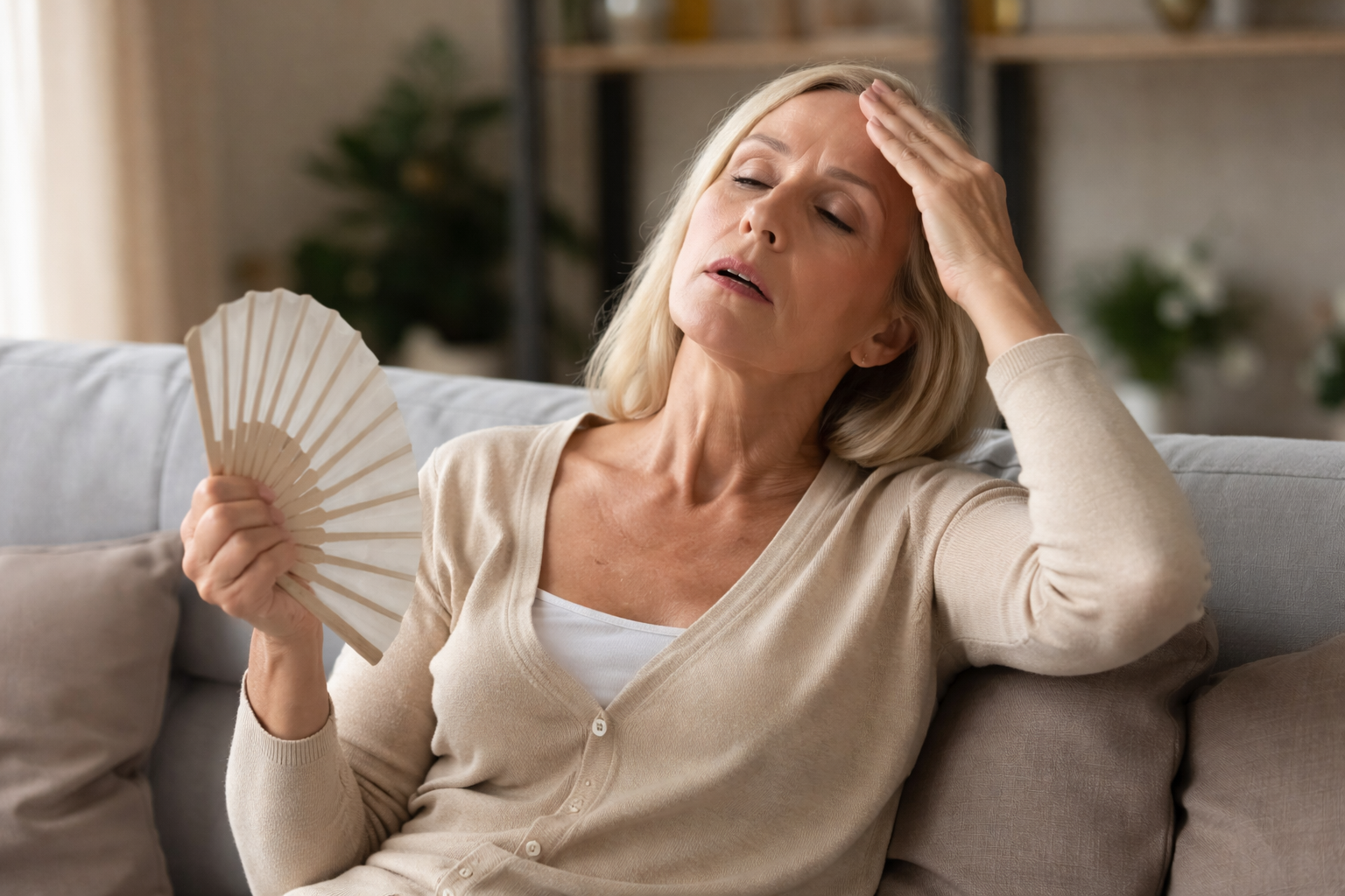 Middle aged woman experiencing perimenopause symptoms such as hot flashes and fatigue while sitting at home