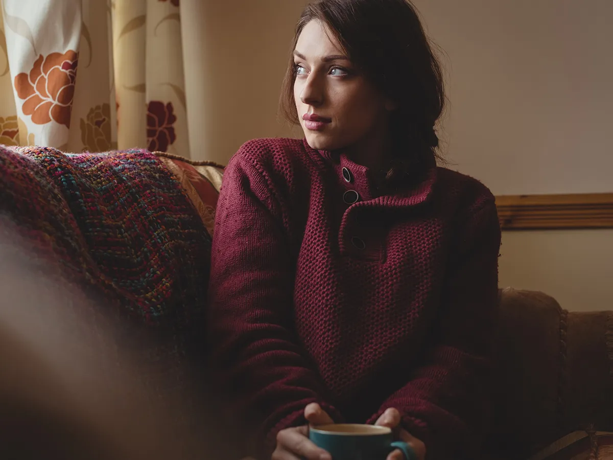 Woman sitting quietly at home, looking away in thought
