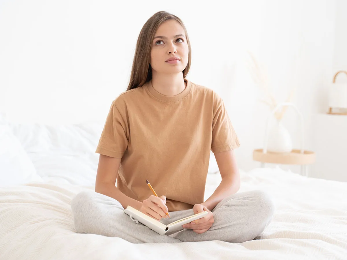 Woman tracking her cycle in a journal at home, feeling more in control after finding PMDD care
