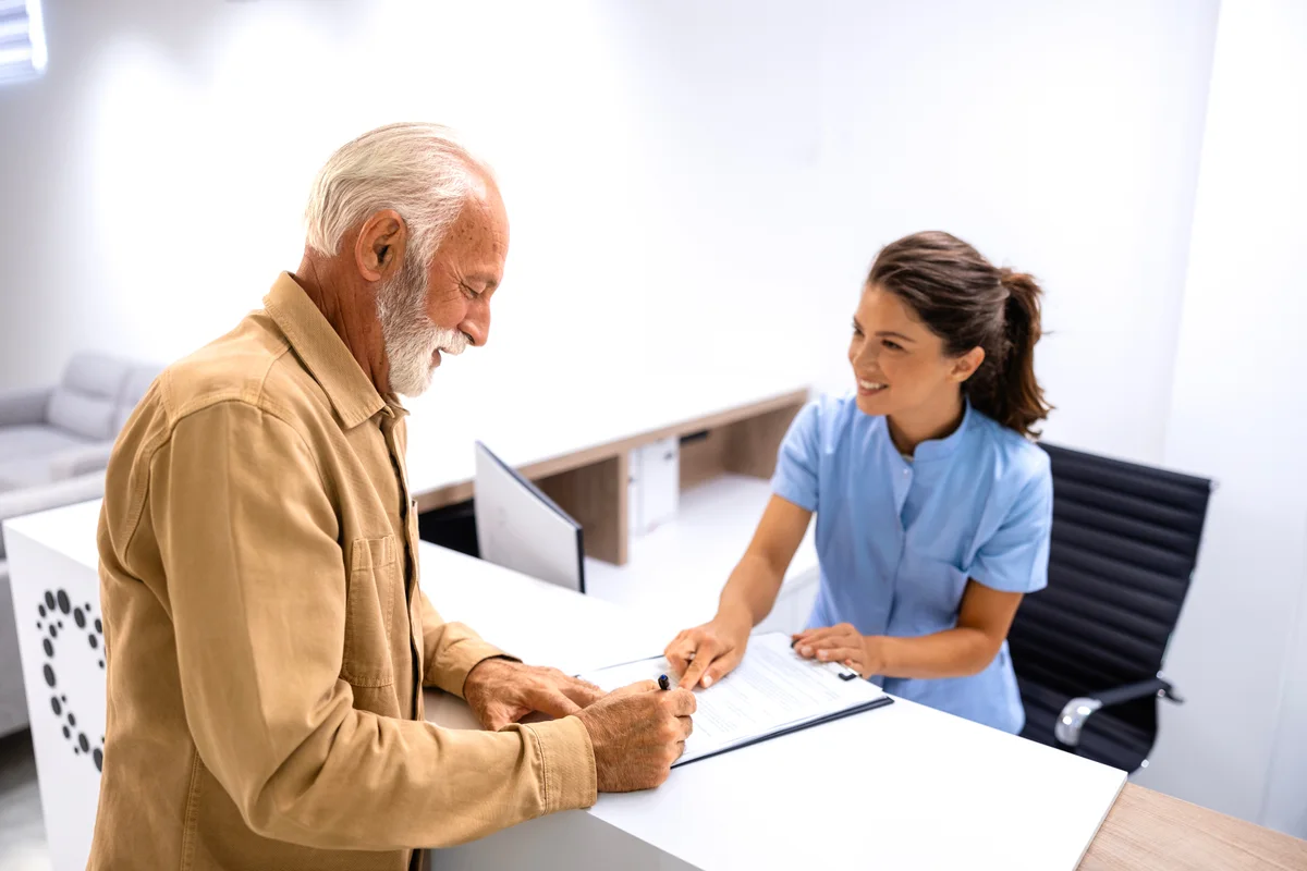 Patient completing plan paperwork with clinic staff at an Elite Primary Physicians Anaheim front desk