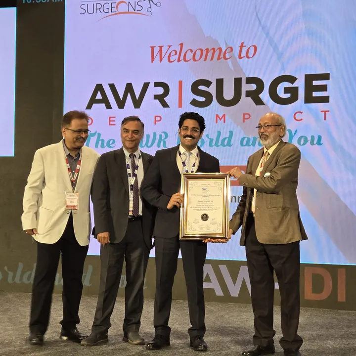 Dr. Kapoor receiving an award on stage at AWR SURGE Deep Impact