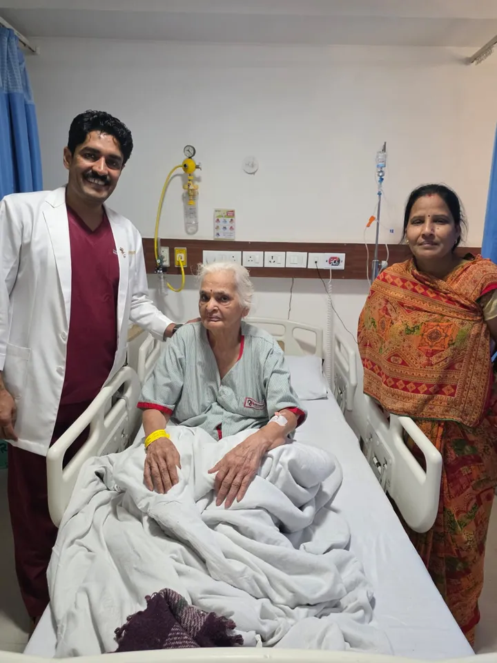 Dr. Kapoor visiting an elderly patient and her family at the bedside
