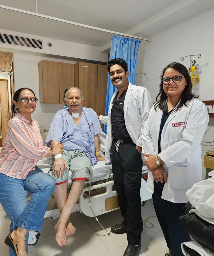 Dr. Kapoor and a colleague with an elderly patient and family at the bedside
