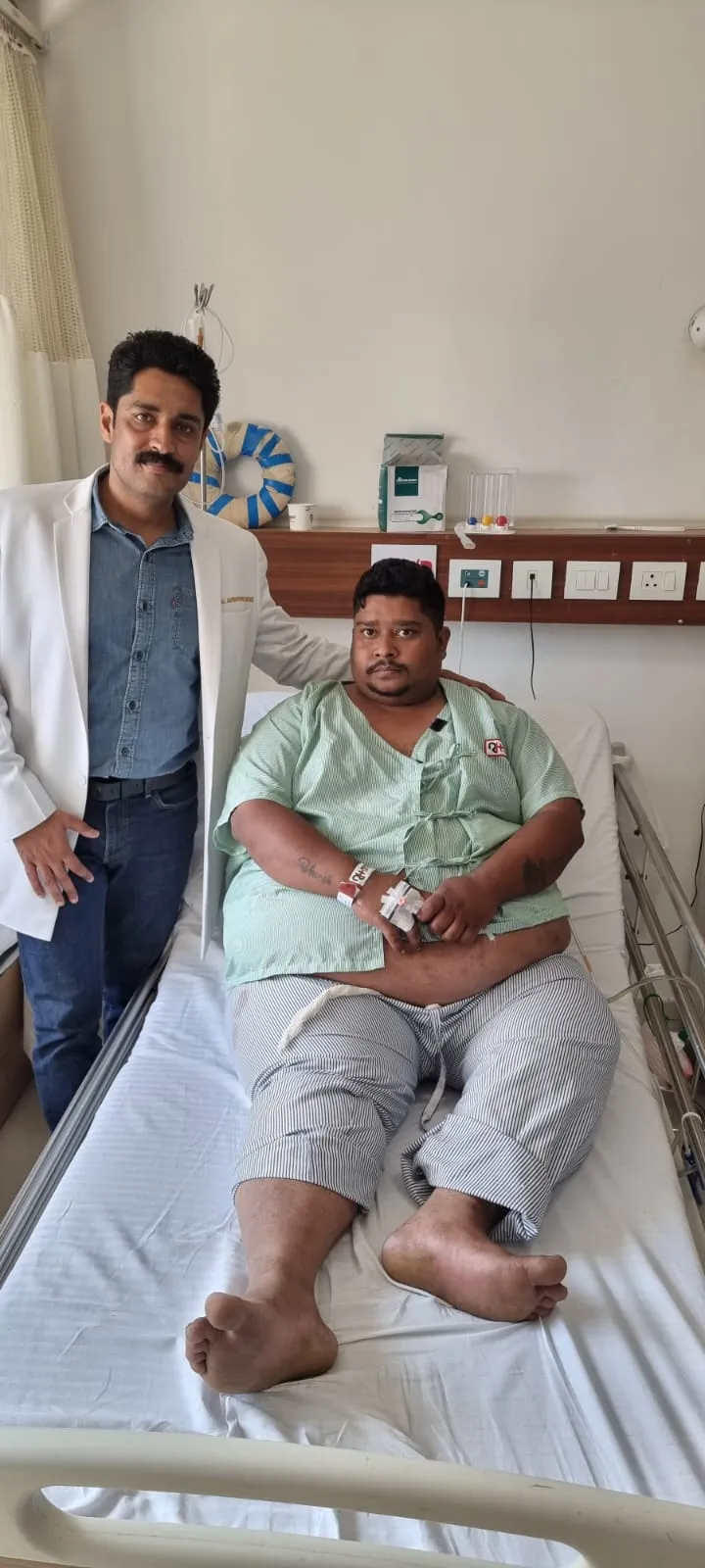 Dr. Kapoor with a recovering patient sitting up in a hospital bed
