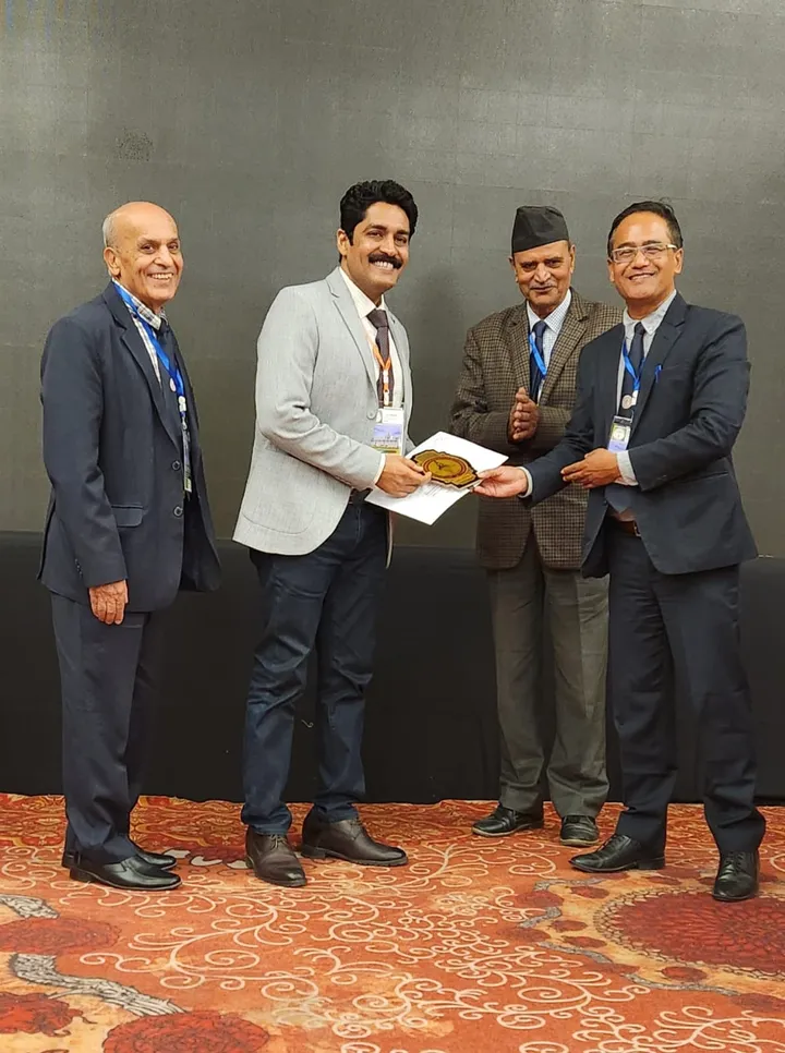 Dr. Kapoor receiving a certificate on stage at a surgical conference