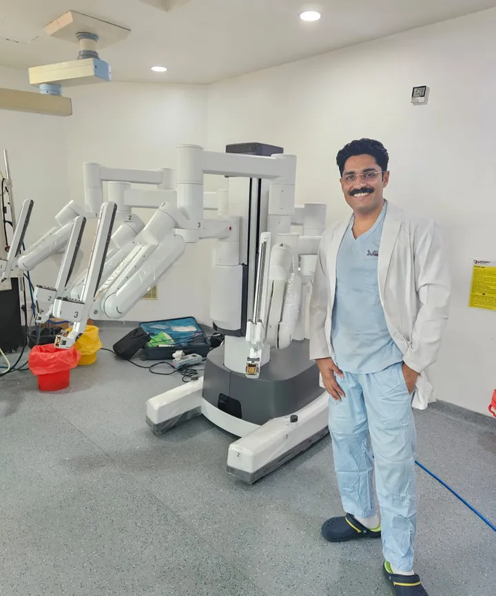 Dr. Kapoor standing beside the da Vinci surgical robot