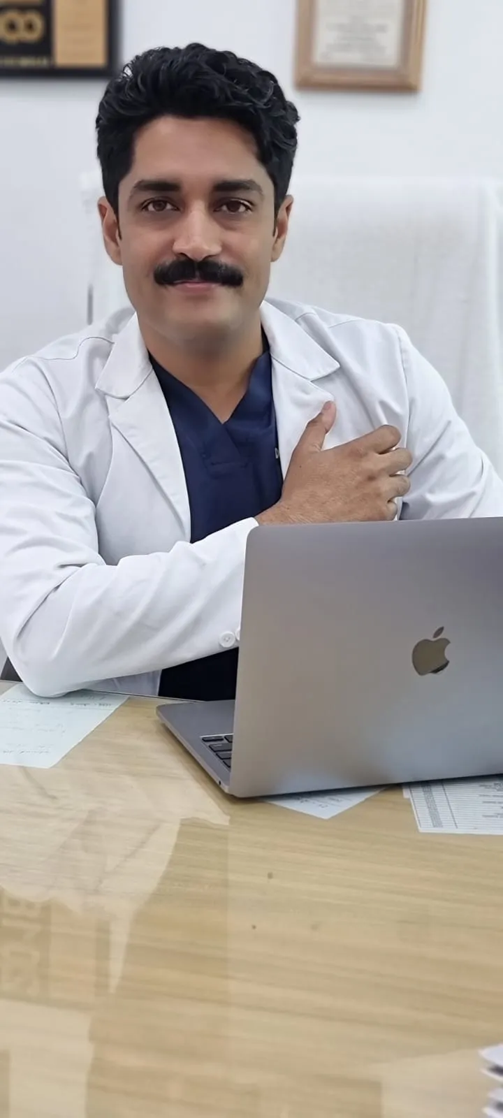 Dr. Kapoor at his desk with a laptop