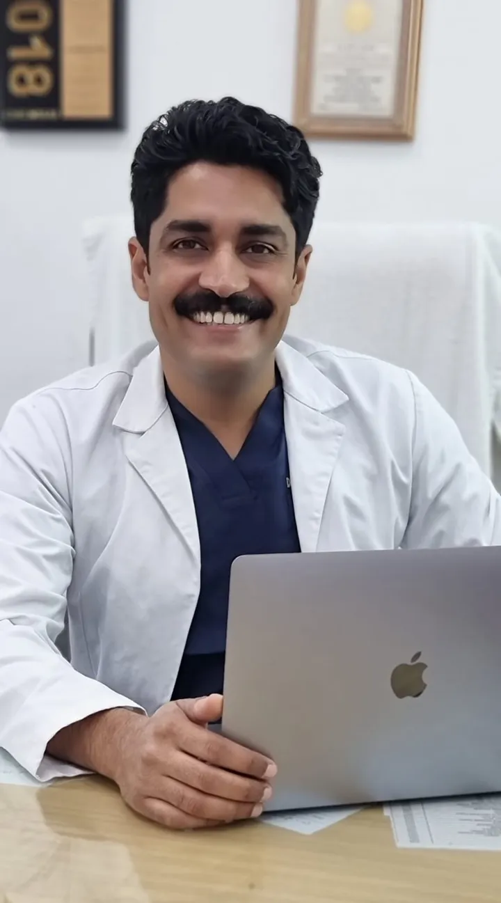 Dr. Kapoor smiling at his desk with a laptop