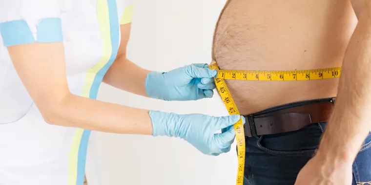 Clinician measuring a patient's waist during a weight assessment