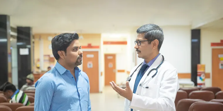 Doctor discussing a diagnosis with a patient in a hospital corridor