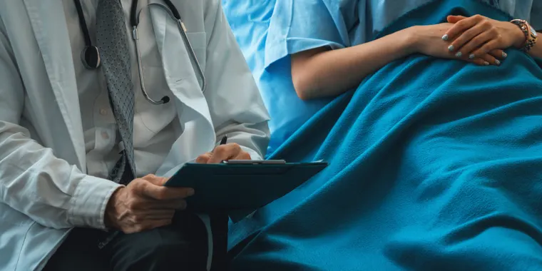 Doctor reviewing notes with a patient resting after a day procedure
