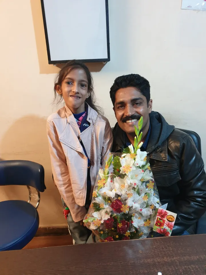 Dr. Kapoor with a young patient holding a bouquet after treatment