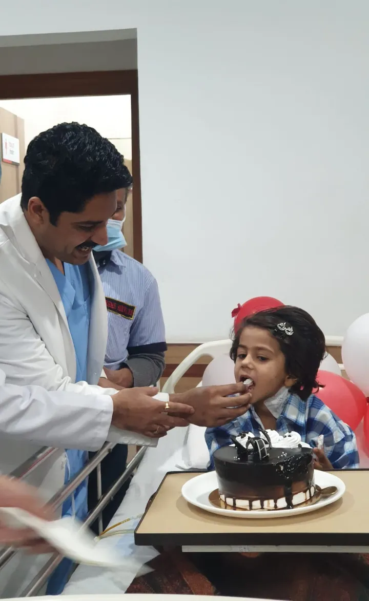Dr. Kapoor feeding cake to a young patient celebrating her recovery