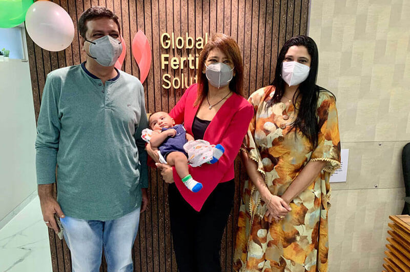  Dr. Goral Gandhi is taking a picture with a family and holding an IVF baby in her hand.
