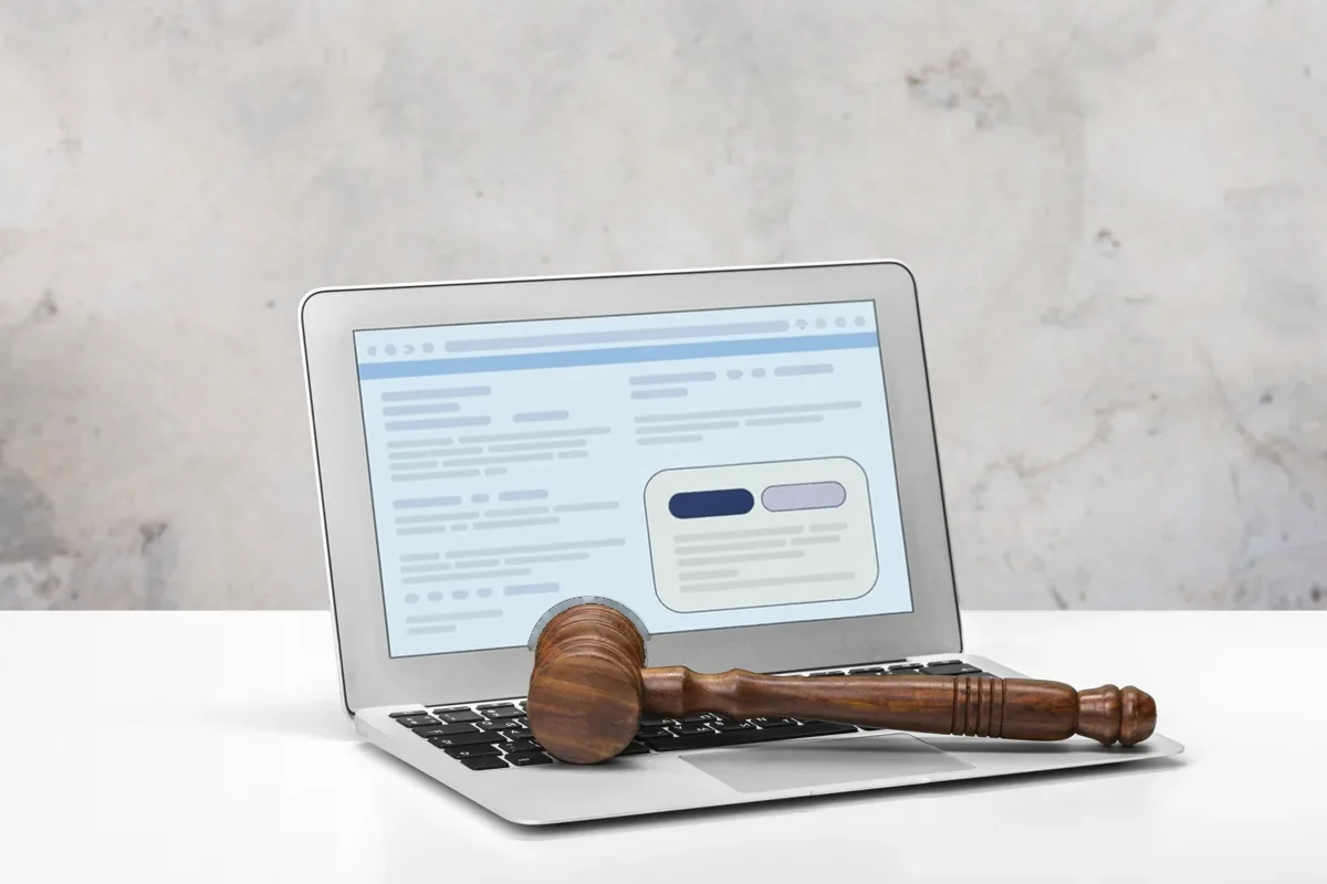 Laptop showing a website with a cookie consent banner, a judge's gavel resting on the keyboard