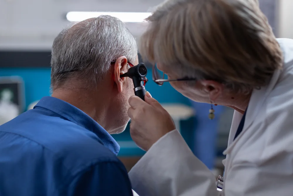 Specialist examining a patient’s ear with an otoscope