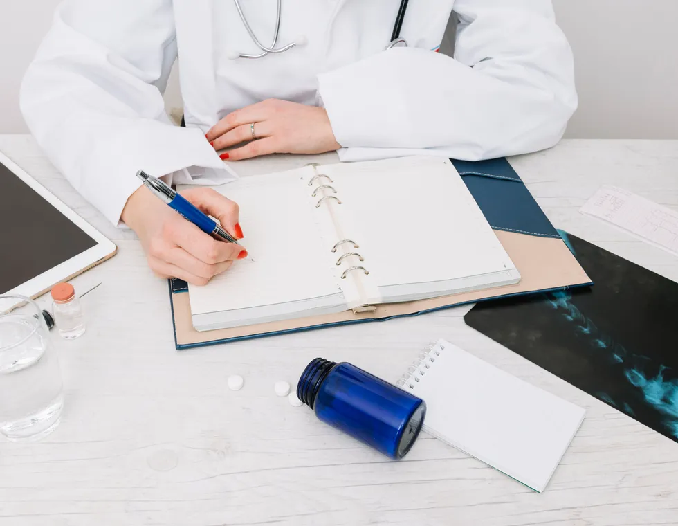Doctor writing research notes alongside medical scans