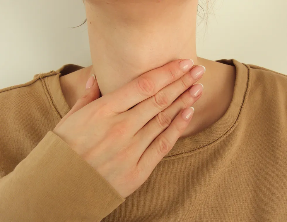 Woman checking a swelling in her neck and throat